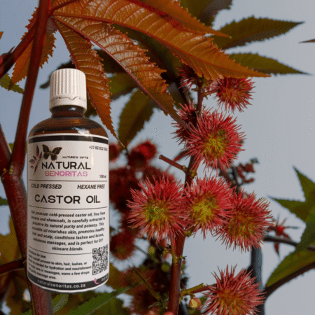 Natural Castor Oil bottle with castor seeds and leaves in the background